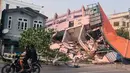 Orang-orang mengendarai sepeda motor melewati sebuah bangunan yang runtuh di Mandalay pada tanggal 28 Maret 2025, setelah gempa bumi di Myanmar tengah. (Foto: AFP)