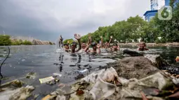 Anak-anak berada dekat tumpukkan sampah saat berenang di rawa pesisir Muara Baru, Cilincing, Jakarta, Minggu (15/8/2021). Anak-anak setempat memanfaatkan rawa sebagai wahana berenang akibat keterbatasan lahan bermain di wilayah pesisir tersebut. (merdeka.com/Iqbal S Nugroho)