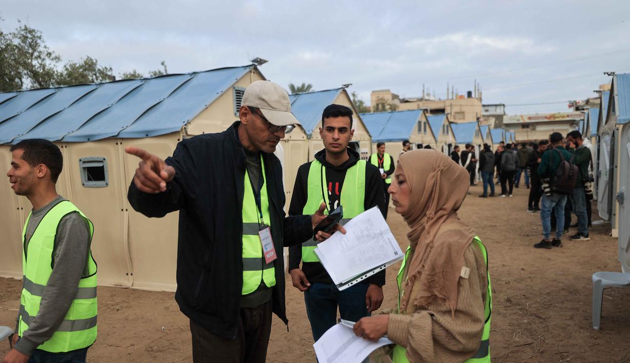 Pemilu ini digelar di tengah ketegangan yang tinggi dan kekhawatiran atas aneksasi wilayah oleh Israel. Tampak dalam foto, petugas pemilu Palestina menyiapkan Tempat Pemungutan Suara (TPS) darurat di tenda-tenda untuk pemilihan kota di Deir el-Balah, Jalur Gaza, pada Sabtu 25 April 2026. (Eyad Baba/AFP)