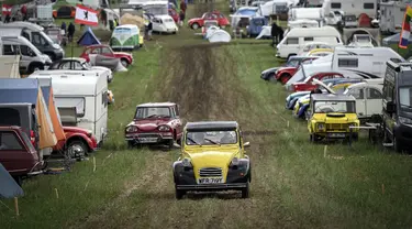 Mobil-mobil melewati kamp selama pertemuan dunia Citroen 2CV Friends di dekat Delemont, Swiss, 26 Juli 2023. (GABRIEL MONNET/AFP)