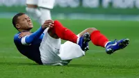 Penyerang timnas Prancis dan PSG, Kylian Mbappe meringis kesakitan setelah terlibat duel dengan kiper timnas Uruguay, Martin Campana dalam laga uji coba di Stade de France, Rabu (21/11). Mbappe mengalami cedera bahu pada menit ke-30 (AP/Francois Mori)