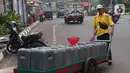 Pedagang mendorong gerobak drigen untuk di isi air bersih di Kembangan, Jakarta, Rabu (13/7/2022). Air bersih yang dijual seharga 5 ribu per drigen tersebut untuk memenuhi kebutuhan air bersih bagi warga sekitar kawasan tersebut. (Liputan6.com/Angga Yuniar)