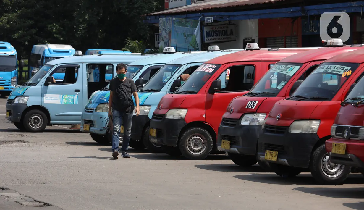 Seorang pria melintasi deretan angkutan kota (angkot) yang terparkir di Terminal Grogol, Jakarta, Sabtu (27/8/2022). Wakil Gubernur DKI Jakarta Ahmad Riza Patria berharap kenaikan tarif ojek online yang dimulai pada 29 Agustus mendatang bisa membuat banyak warga ibu kota beralih ke angkutan umum. (Liputan6.com/Angga Yuniar)