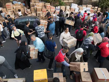 Sejumlah relawan menyalurkan bantuan untuk para korban kebakaran Grenfell Tower di Kensington utara di London, Inggris (15/6). Korban jiwa akibat kebakaran di apartemen berlantai 24 di London mencapai 12 orang. (AP Photo/Tim Ireland)