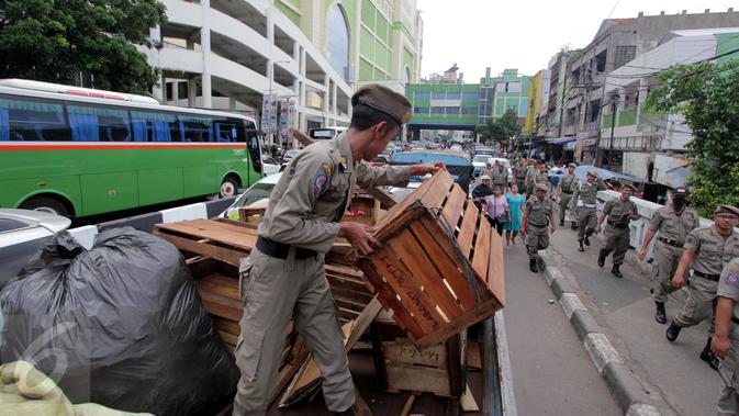 Barang-barang dari PKL diangkut Satpol PP di Pasar Tanah Abang, Jakarta, Kamis (4/5). Penertiban dilakukan agar tidak menggangu fungsi pedestrian untuk pejalan kaki. (Liputan6.com/Johan Tallo)