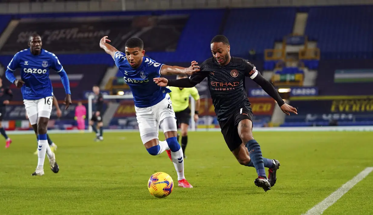 Pemain Manchester City Raheem Sterling (kanan) memperebutkan bola dengan pemain Everton Mason Holgate pada pertandingan Liga Inggris di Stadion Goodison Park, Liverpool, Inggris, Rabu (17/2/2021). Manchester City menang 3-1. (Jon Super/Pool via AP)