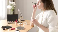 Seorang perempuan sedang bercermin sambil menggunakan make up (Foto Dok: Freepik/freepik).