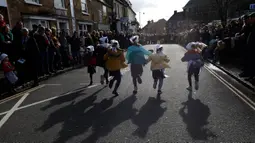 Anak-anak sekolah-sekolah lokal mengambil bagian dalam lomba lari sembari membawa wajan berisi pancake di Olney, Buckinghamshire, Inggris, Selasa (25/2/2020). Peserta kompetisi yang sudah ada sejak tahun 1445 ini harus membolak-balikan pancake sambil tetap berlari. (AP/Alastair Grant)