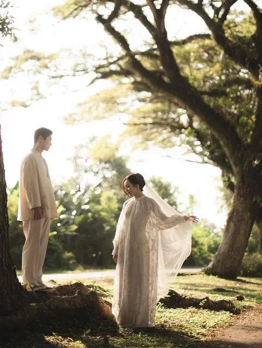 Beby memilih pakaian tertutup pada sesi pre weddingnya tersebut. Ia mengenakan maxi dress lengan panjang brokat warna putih dengan kerah tinggi dari desainer lokal Sapto Djojokartiko. [@bebytsabina]