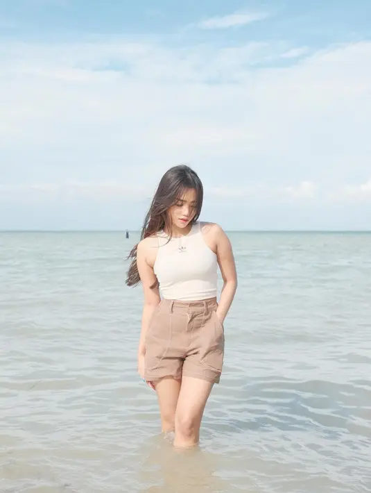 Tampilan kasual yang nyaman juga stylish, bisa tiru gaya Fuji An yang memadukan crop tank top putihnya dengan shorts warna coklat muda yang selaras dengan warna pasir pantainya.  [Foto: IG/fuji_an].