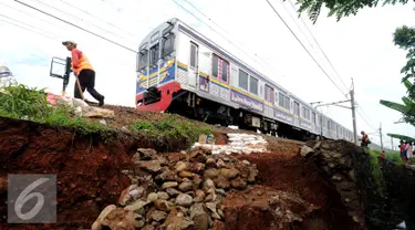 Pekerja meletakkan batuan untuk memperkuat struktur tanah yang longsor dekat rel KRL di sekitar Kampung Pabuaran, Bogor, Rabu (25/11/2015). Sebelumnya, Selasa (24/11) tanah di sekitar rel KM 38 dan 39 mengalami longsor. (Liputan6.com/Helmi Fithriansyah)