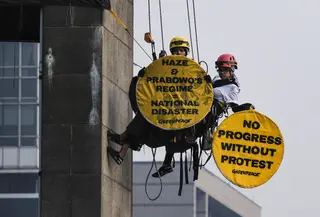 Aktivis Greenpeace Indonesia bergelantungan di Patung Selamat Datang sambil membentangkan poster berisi pesan protes di kawasan Bundaran Hotel Indonesia, Jakarta, Selasa (20/10/2026). Aksi tersebut digelar bertepatan dengan dua tahun pelantikan Presiden Prabowo Subianto. Para aktivis mendesak pemerintah mengambil langkah untuk mengatasi krisis iklim yang kian memburuk dan kenaikan biaya hidup. (BAY ISMOYO/AFP)