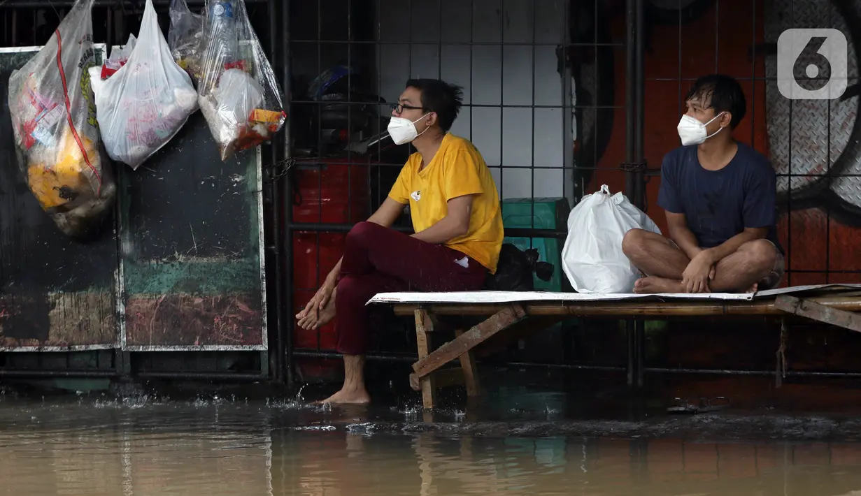 Warga duduk-duduk saat banjir menggenangi kawasan Jalan Wolter Monginsidi Jakarta dan sekitarnya, Sabtu (20/2/2021). Hujan yang mengguyur Jakarta sejak Jumat (19/2) membuat sejumlah titik di Jakarta terendam banjir. (Liputan6.com/Helmi Fithriansyah)