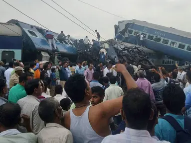 Polisi dibantu warga lokal mengevakuasi para korban dari sebuah kereta api yang tergelincir hingga keluar jalur di Negara Bagian Uttar Pradesh, India, Minggu (20/8). Sedikitnya lebih dari 20 penumpang tewas akibat kecelakaan tersebut. (AP Photo)