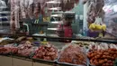 Seorang tukang daging menunggu pelanggan dari balik sekat tirai pelindung plastik di pasar La Asuncion di Villa Nueva, Guatemala City pada 20 Juli 2020. Kios di pasar itu menggunakan tirai pelindung plastik untuk menjaga jarak fisik guna mengurangi resiko penyebaran virus Corona. (Johan ORDONEZ/AFP)