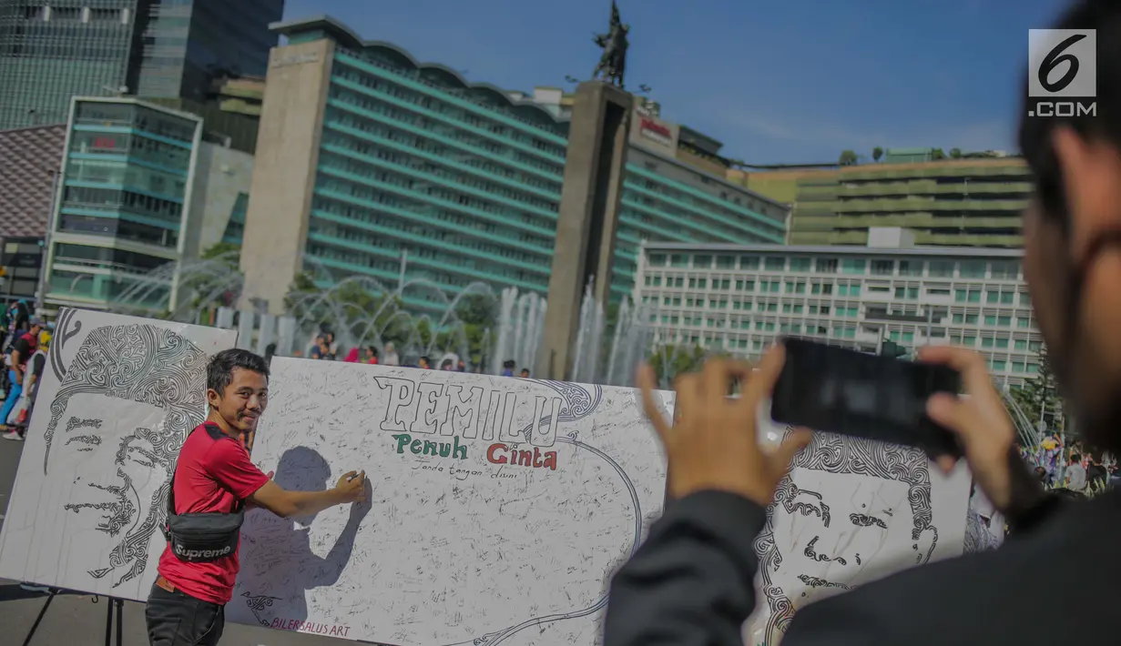 Masyarakat menandatangani dilukisan capres 01 dan 02  yang bertema ‘ Pemilu Penuh Cinta’  saat Car Free day di kawasan Bundaran HI, Jakarta, MInggu (14/4). Kampanye tersebut untuk mengajak masyarakat untuk berpartisipasi dalam Pemilu secara Damai. (Liputan6.com/Faizal Fanani)