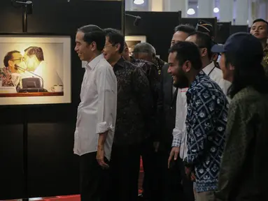 Presiden Joko Widodo melihat karya foto yang dipajang pada pameran foto jurnalistik Setahun Kerja Jokowi-JK di Museum Bank Mandiri, Jakarta, Jumat (18/12). Foto tersebut merupakan karya para anggota Pewarta Foto Indonesia (Liputan6.com/Faizal Fanani)