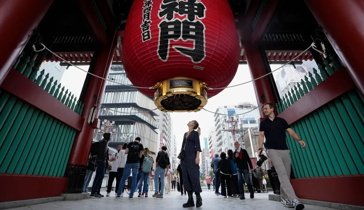 Seorang turis asing melihat ke dalam untuk melihat bagian dalam lentera terkenal di gerbang kuil Buddha Sensoji di distrik hiburan Asakusa, Tokyo, Jepang, Senin (17/10/2022). Kuil ini menjadi salah satu destinasi favorit di Asakusa, sekitar 30 juta wisatawan datang ke tempat ini sepanjang tahunnya. (AP Photo/Hiro Komae)