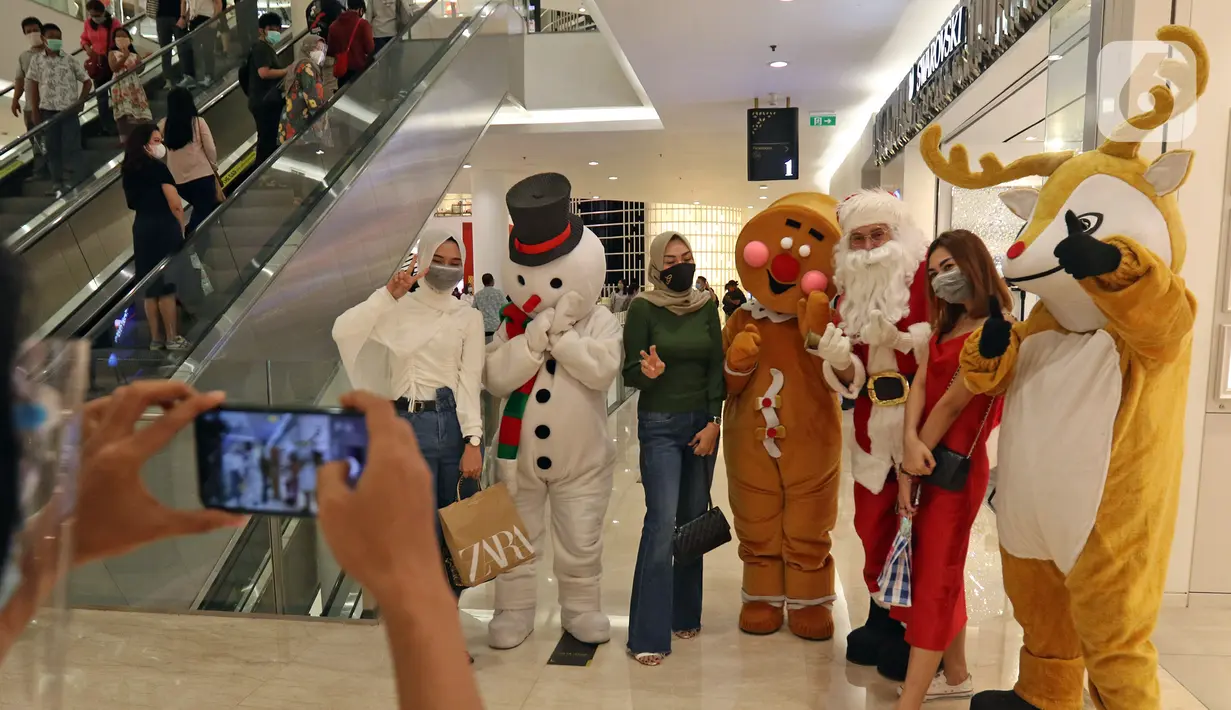 Petugas yang mengenakan kostum Sinterklas melayani foto bersama pengunjung di Senayan City Mall, Jakarta, Jumat (25/12/2020). Kegiatan tersebut bertujuan untuk melengkapi kebahagiaan Natal tahun 2020. (Liputan6.com/Herman Zakharia)