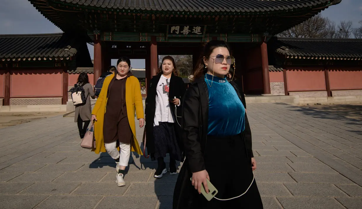 Pengunjung menenteng ponselnya di gerbang istana Changdeokgung di Seoul , Korea Selatan (2/4). Korea Selatan sedang bersiap untuk meluncurkan jaringan seluler 5G pertama di dunia pada 5 April. (AFP Photo/Ed Jones)