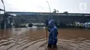 Seorang sopir melintasi banjir di Pool Blue Bird Kramat Jati, Jakarta, Rabu (1/1/2020). Akibat banjir setinggi hingga leher orang dewasa tersebut pool berhenti operasi dan sopir terpaksa diliburkan hingga waktu yang belum ditentukan. (merdeka.com/Iqbal S. Nugroho)