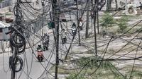 Kendaraan melintas dekat instalasi kabel yang semrawut di Jalan Raya Bekasi, Cakung, Jakarta, Rabu (30/9/2020). Minimnya perawatan pascapembebasan lahan permukiman untuk proyek Tol Dalam Kota membuat jaringan kabel listrik di sepanjang jalan tersebut semrawut. (merdeka.com/Iqbal S. Nugroho)