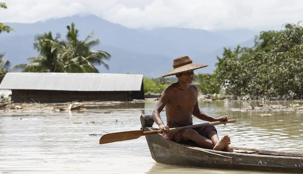 Seorang warga menggunakan perahu untuk melintasi jalanan yang terendam banjir di kawasan Kalay, Sagaing, Myanmar, Minggu (2/8/2015). Setidaknya 21 orang tewas akibat banjir yang melanda empat wilayah di Myanmar. (REUTERS/Soe Zeya Tun)