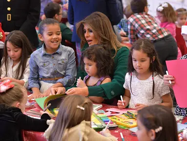 Ibu Negara AS Melania Trump membantu anak-anak membuat kartu Natal di Kampanye Program Korps Marinir AS "Toys For Tots" di Joint Base Anacostia-Bolling, Washington (13/12). Acara ini merupakan kegiatan menyambut Natal di AS. (AFP Photo/mandel Ngan)