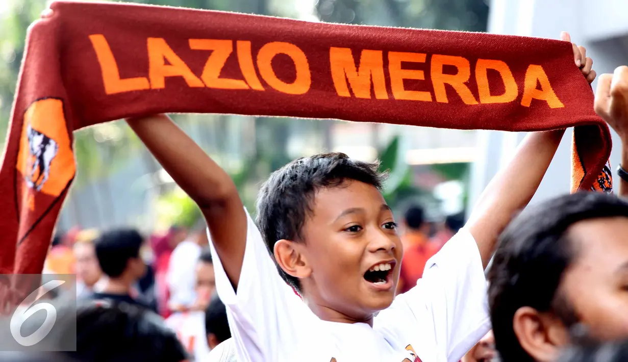 Seorang anak pengemar AS Roma membentangkan shal sebelum menyaksikan tim kesayangannya bertanding di Gelora Bung Karno, Jakarta, Sabtu (25/7/2015). Tim berjuluk Giallorossi akan menggelar pertandingan intern antara skuadnya. (Liputan6.com/Herman Zakharia)