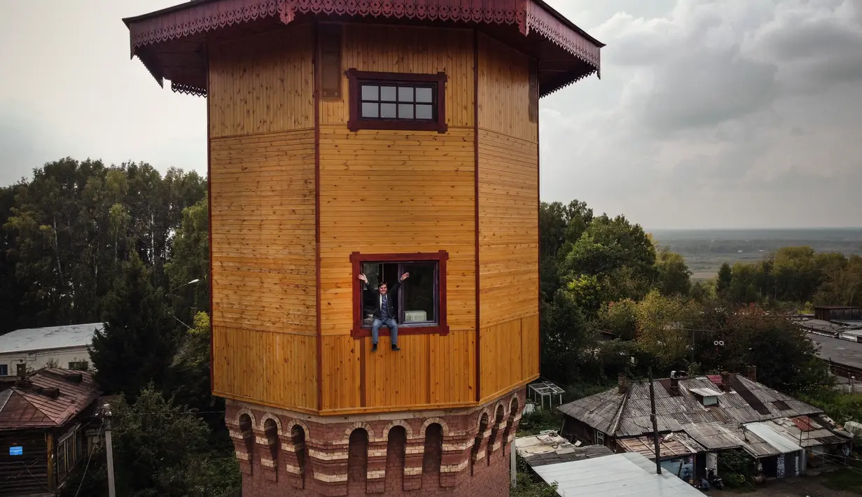 Pengusaha Rusia Alexander Lunev duduk di jendela bekas menara air, yang diubah menjadi apartemen, di kota Tomsk, Siberia pada 7 September 2020. Alexander Lunev, mantan presenter radio dari Kota Tomsk telah membeli menara air berusia 125 tahun dari kotamadya pada tahun 2012. (Alexander NEMENOV / AFP)