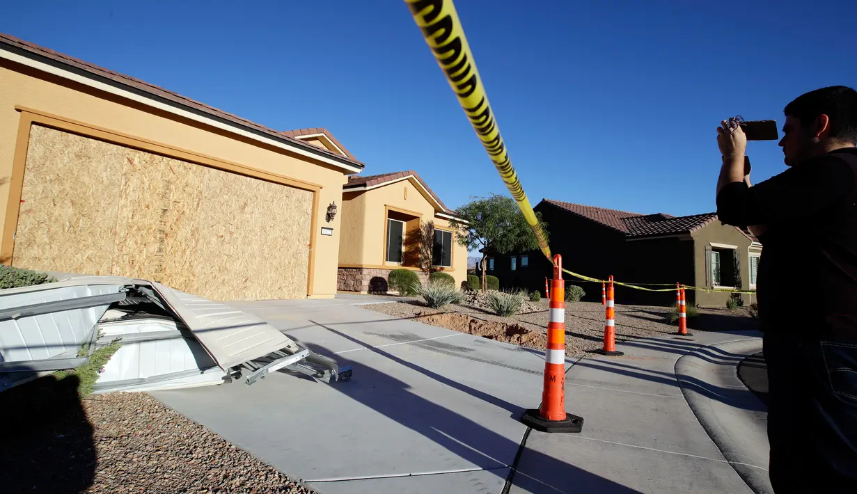 Seorang pria mengambil gambar rumah pelaku penembakan Las Vegas, Stephen Paddock (64), di Mesquite, Nevada, Senin (2/10). Rumah yang didominasi warna cokelat itu dilengkapi satu garasi dan tanpa memiliki pagar di sekitarnya. (AP Photo/Chris Carlson)