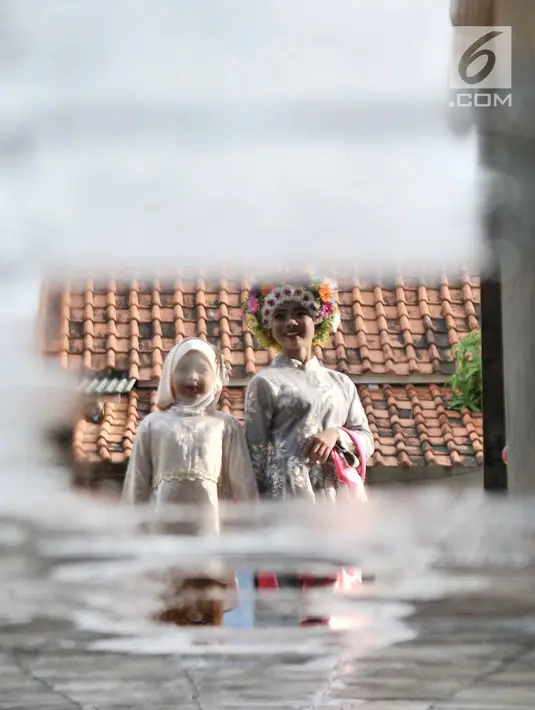Seorang gadis didampingi adiknya saat berjalan untuk mengikuti upacara adat Ngarot di Desa Lelea, Indramayu, Jawa Barat, Rabu (19/12). Ngarot merupakan tradisi yang diikuti gadis 'perawan'. (Merdeka.com/Iqbal Nugroho)