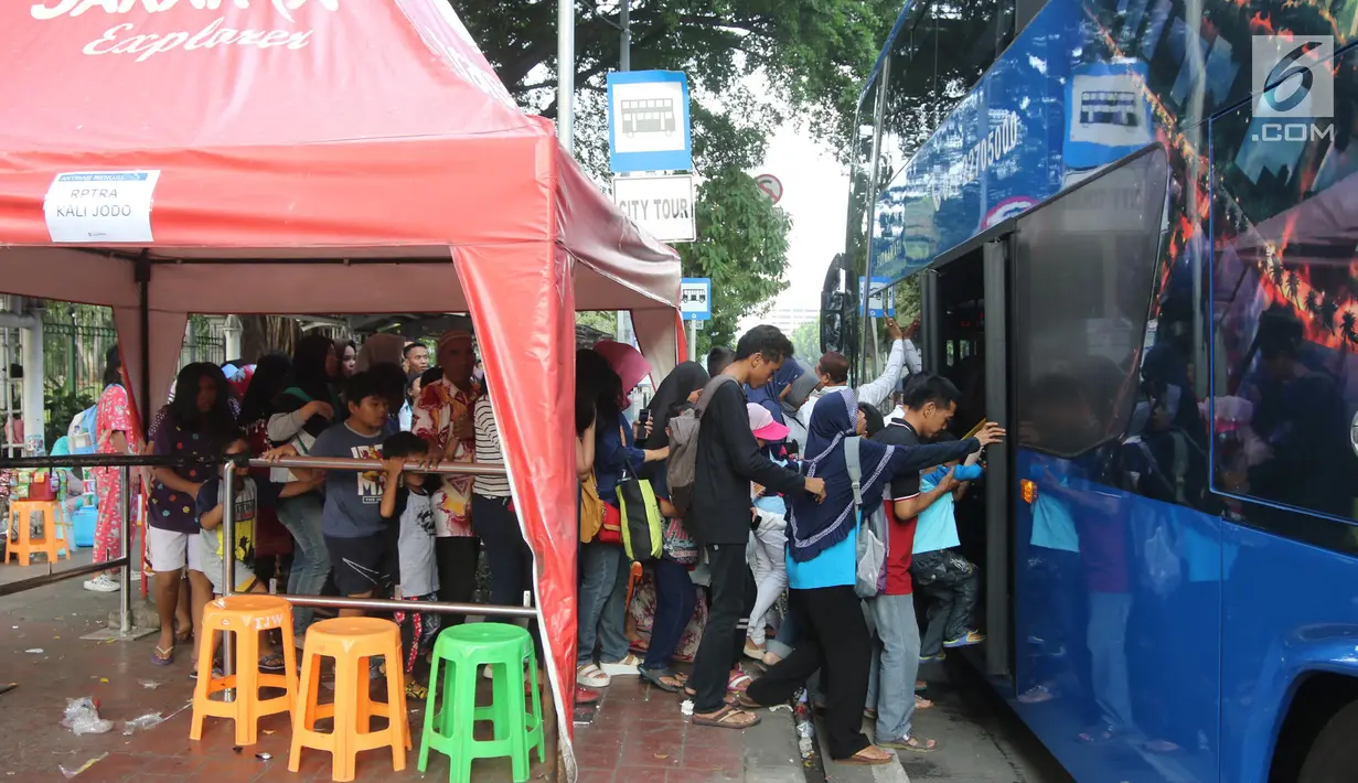 Warga menaiki bus tingkat wisata keliling Ibu Kota di kawasan Monas, Jakarta, Sabtu (16/6). Libur Hari Raya Idul Fitri dimanfaatkan oleh sebagian masyarakat Jakarta untuk berlibur ketempat wisata bersama keluarga. (Liputan6.com/Arya Manggala)