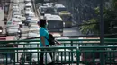 Pejalan kaki memakai masker pelindung saat melintasi jembatan layang selama kabut asap menyelimuti Bangkok (14/1). Tingkat kabut asap yang sangat tinggi diperburuk oleh pola cuaca yang meningkatkan kewaspadaan di seluruh Asia. (AP Photo/Sakchai Lalit)