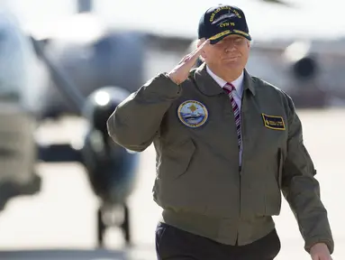 Presiden AS, Donald Trump memberi hormat saat berjalan menuju pesawat Air Force One sebelum berangkat dari Pangkalan Udara Langley di Virginia, (2/3). Trump tampak gagah mengenakan jaket panglima tertinggi Navy Seal. (AFP Photo / Saul Loeb)