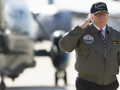 Presiden AS, Donald Trump memberi hormat saat berjalan menuju pesawat Air Force One sebelum berangkat dari Pangkalan Udara Langley di Virginia, (2/3). Trump tampak gagah mengenakan jaket panglima tertinggi Navy Seal. (AFP Photo / Saul Loeb)