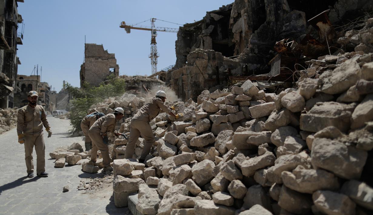 Pekerja menyingkirkan puing-puing dari toko-toko yang rusak di Kota Tua Aleppo, Suriah, Sabtu (27/7/2019). Kendati sebagian besar pasar masih tutup setelah pertempuran besar tiga tahun lalu, kegiatan ekonomi perlahan mulai tumbuh di kota terbesar di Suriah tersebut. (AP Photo/Hassan Ammar)