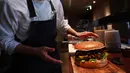 Chef dari restoran The Oak Door, Patrick Shimada berpose dengan burger raksasa di hotel Grand Hyatt Tokyo, Senin (1/4). Hamburger ini memiliki diameter 25 centimeter dan berisi foie gras, daging sapi Jepang, dan jamur truffle hitam segar. (CHARLY TRIBALLEAU/AFP)