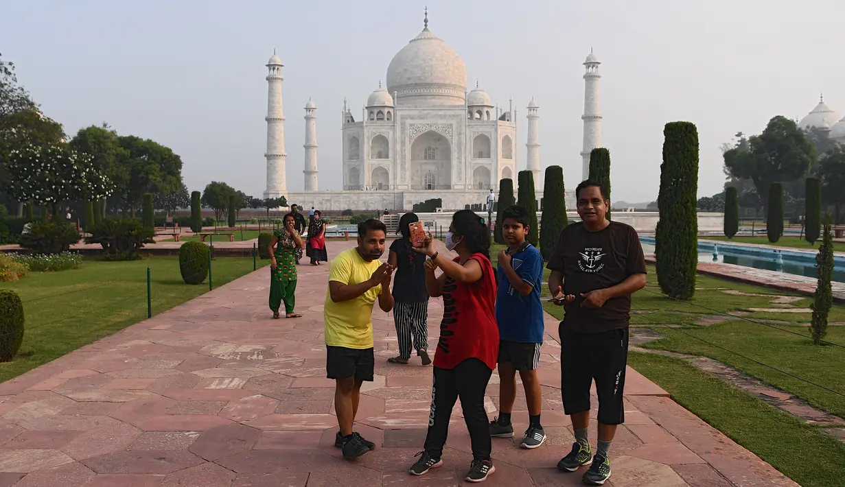 Turis mengabadikan foto saat mengunjungi Taj Mahal di Agra, India pada Senin (21/9/2020). Taj Mahal kembali dibuka untuk umum dalam gerakan simbolis seperti biasa, bahkan ketika India tampaknya akan mengambil alih AS sebagai pemimpin global dalam infeksi Virus Corona COVID-19. (Sajjad HUSSAIN/AFP)