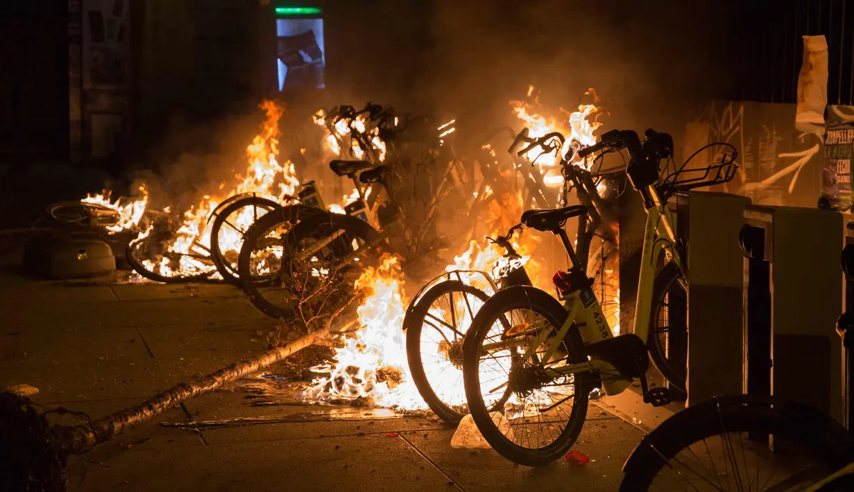 Sejumlah sepeda dibakar saat bentrokan terkait kematian seorang pedagang kaki lima di distrik Lavapies di Madrid (15/3). Pedagang bernama Mmame Mbage diduga tewas setelah dikejar-kejar aparat kepolisian. (AFP Photo/Olmo Calvo)