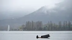 Seorang awak perahu Kashmir mengayuh sebuah perahu saat hujan di Danau Dal di Srinagar (20/3). Danau Dal dijuluki sebagai Jewel in the Crown of Kashmir atau Srinagar Jewel. (AFP Photo/Tauseef Mustafa)