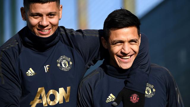 Pemain Manchester United, Marcos Rojo dan Alexis Sanchez, tersenyum saat latihan jelang laga 16 besar Liga Champions. (AFP/Franck Fife)