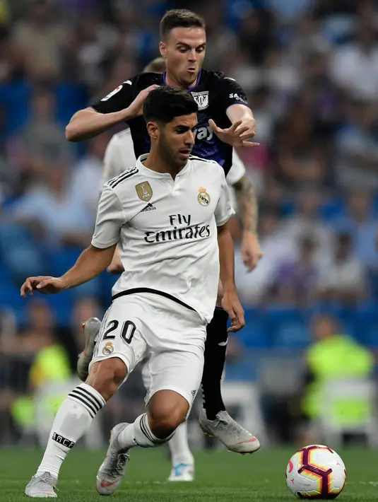 Gelandang Real Madrid, Marco Asensio berebut bola dengan pemain Leganes, Javier Eraso pada laga leg pertama babak 16 besar Copa del Rey di Santiago Bernabeu, Rabu (9/1). Real Madrid sukses mengandaskan Leganes dengan skor 3-0. (GABRIEL BOUYS / AFP)