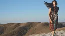 Di atas gunung yang memiliki pemandangan begitu indah, Nadine pun tampak mempesona dengan dress batiknya. Ia pun lagi-lagi membiarkan rambut panjangnya terurai dan tertiup angin seperti ini. (Instagram/nadinelist)