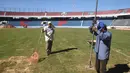 Dua suporter mengecek rumput lapangan saat menyelesaikan pembangunan stadion baru di Asuncion, Paraguay (22/6). Pembangunan stadion memiliki nilai proyek USD 15 juta atau Rp 199 miliar tersebut. (AFP Photo/Norberto Duarte)