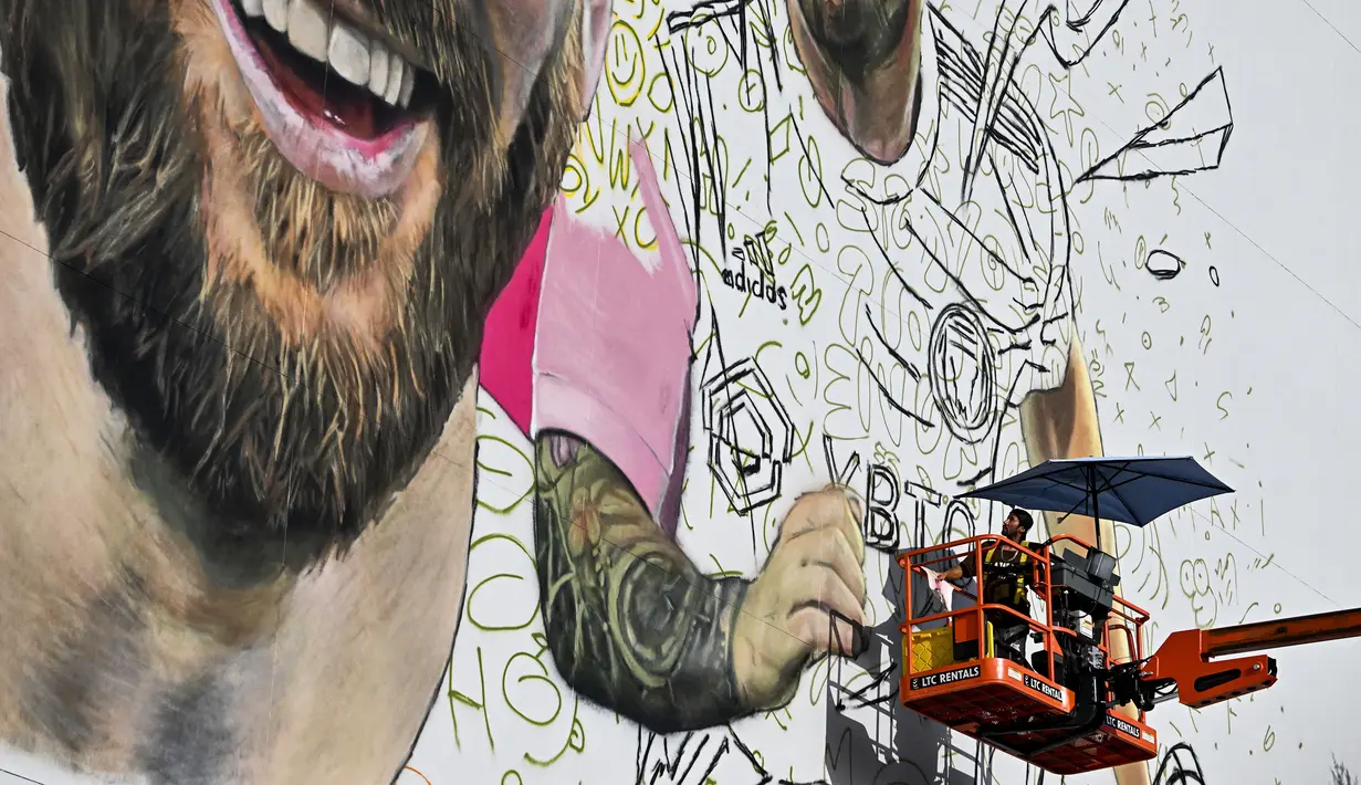 <p>Seniman Argentina, Maximiliano Bagnasco sedang mengerjakan mural besar bergambar Lionel Messi di Wynwood, Miami, 10 Juli 2023. La Pulga akan melakukan debutnya di Inter Miami pada 21 Juli di Piala Liga. (AFP/Chandan Khanna)</p>