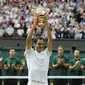 Roger Federer mengangkat trofi Wimbledon usai kalahkan Marin Cilic 6-3, 6-1, 6-4 di final, Minggu (16/7/2017). (AFP/Adrian Dennis)