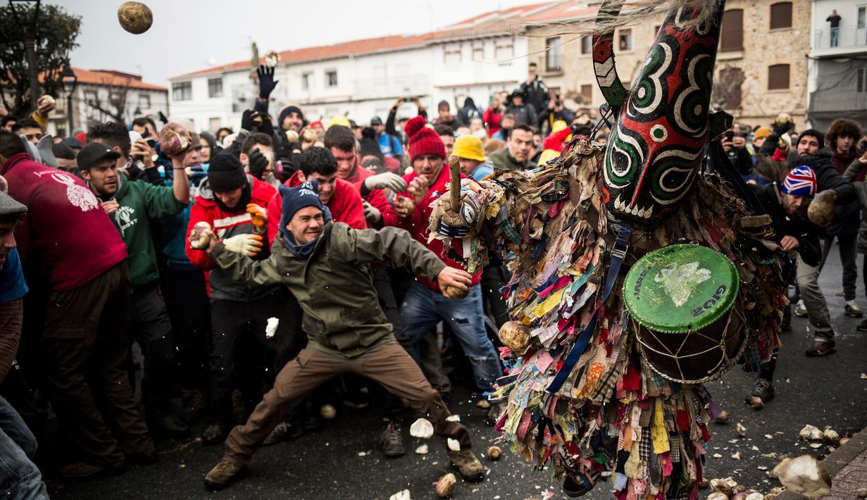 Orang-orang melempari seorang pria berkostum ala setan dengan sayuran lobak selama Festival Jarramplas di kota Piornal, Spanyol, Sabtu (19/1). Sosok "setan" itu disebut dengan Jarramplas yang dikenakan salah satu pemuda desa terpilih. (AP/Javier Fergo)
