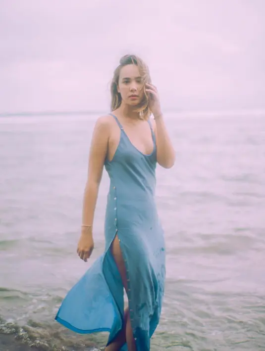 Bukan bikini, Pamela Bowie tampak mengenakan long dress tanpa lengan berwarna biru, dengan detail slit-button di bagian kanan dan kiri dress. Foto: Instagram.