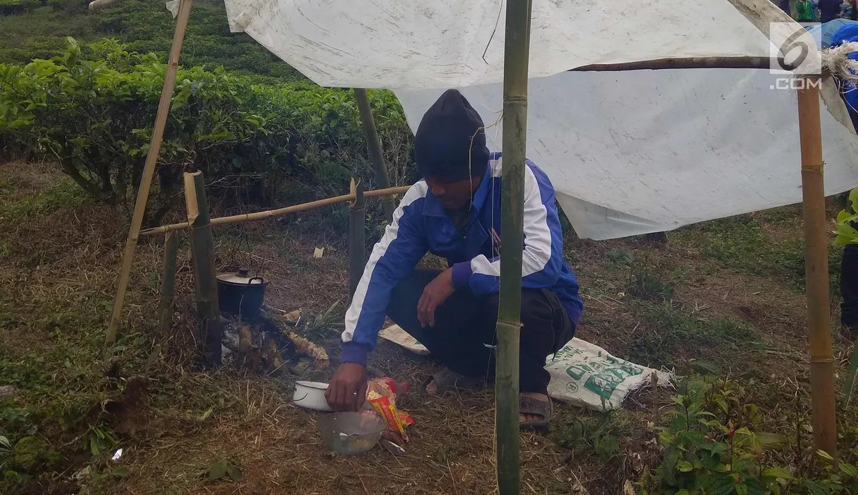 Seorang warga membuat makanan di tenda pengungsian di perkebunan teh di Cialahab, Desa Melasari, Nanggung, Bogor, Rabu (24/1). Mereka mengungsi karena takut terjadi gempa susulan. (Liputan6.com/Ahmad Sudarno)
